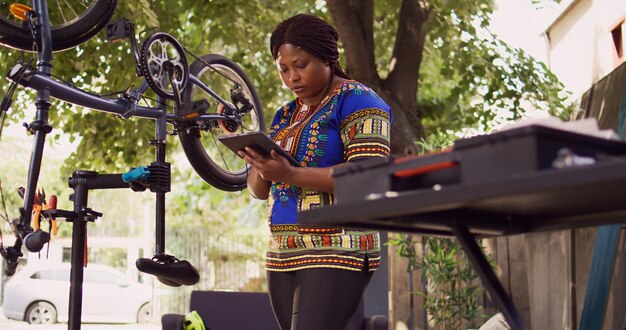 Photo femme utilisant une tablette pour l'entretien du vélo