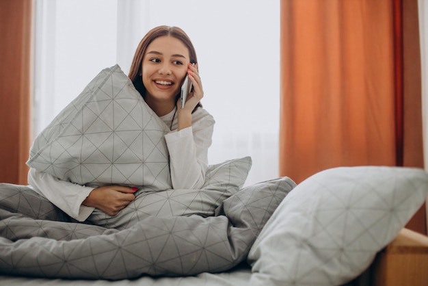 Femme utilisant le téléphone au lit le matin