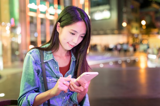 Femme utilisant un téléphone intelligent dans la ville la nuit