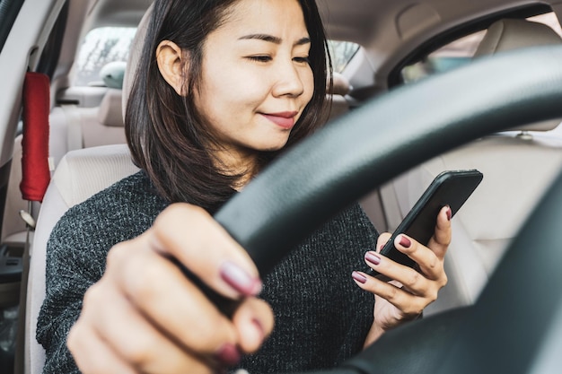 Femme utilisant un téléphone intelligent pendant la conduite d'une voiture