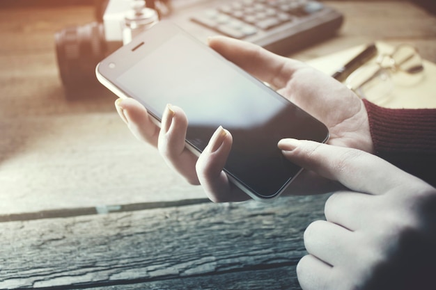 Femme utilisant un téléphone intelligent et une tasse de café sur la table de travail