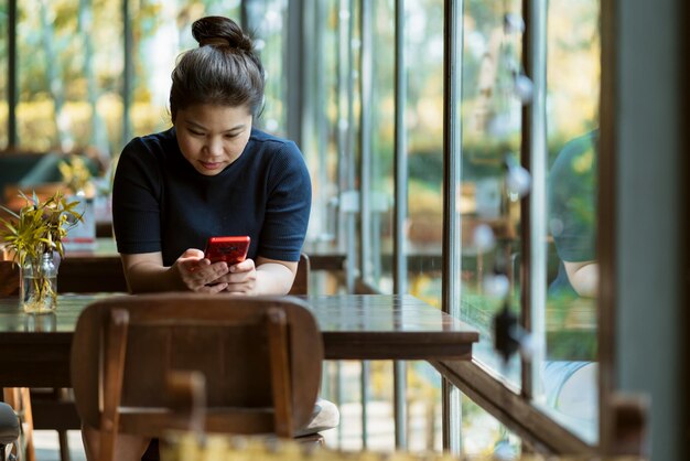 Femme utilisant un téléphone portable alors qu'elle est assise dans un restaurant