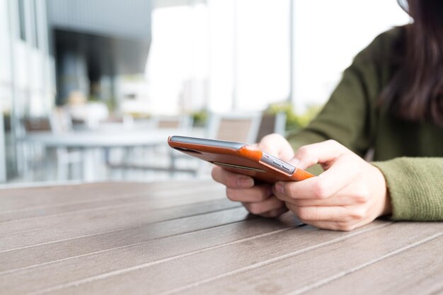 Femme utilisant un téléphone portable au café en plein air