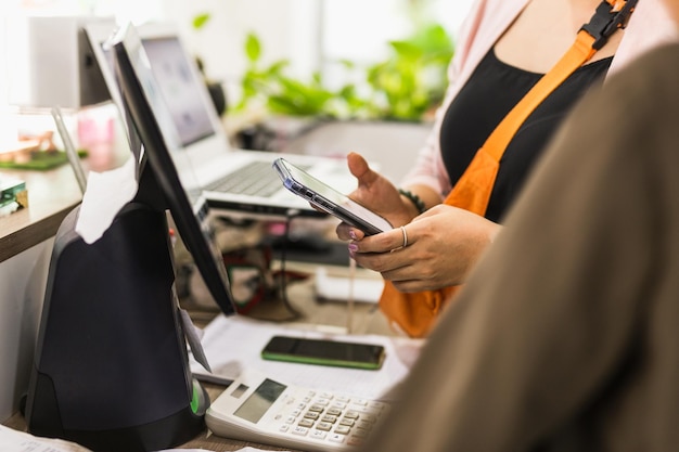 Femme utilisant un téléphone portable au comptoir de la caisse dans le café propriétaire d'une petite entreprise de vente au détail