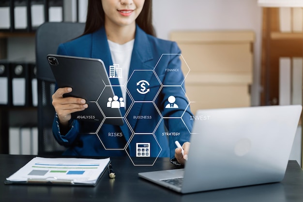 Femme utilisant un téléphone portable dans un bureau moderne avec un ordinateur portable et une tablette numérique avec diagramme d'icône VR au bureau à la lumière du matin