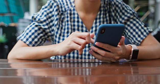 Femme utilisant un téléphone portable dans un café en plein air