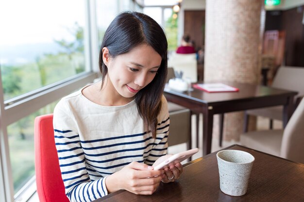 Femme utilisant un téléphone portable dans un café