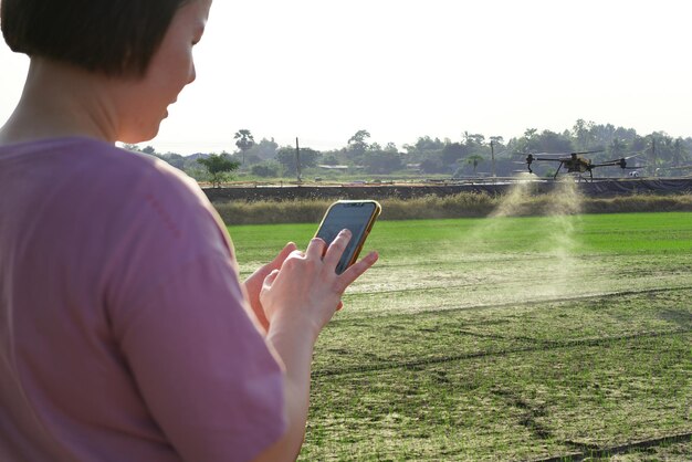 Photo femme utilisant un téléphone portable dans une ferme entourée par le contrôle de la ferme agriculture petrol drone sprayer