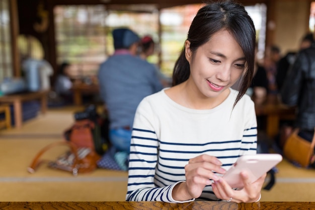 Femme utilisant un téléphone portable dans un restaurant japonais