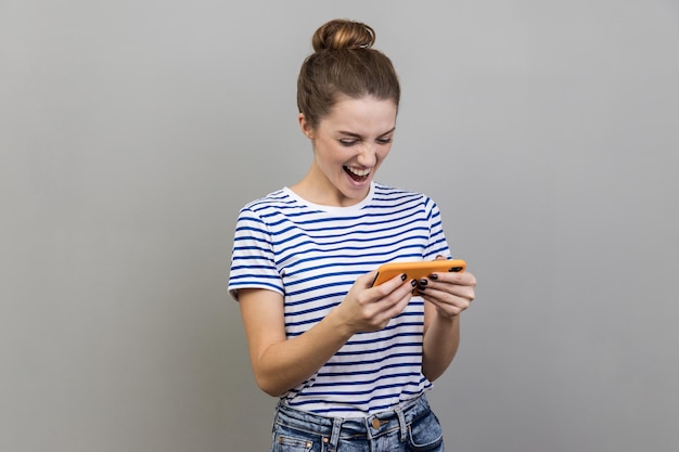 Femme utilisant un téléphone portable avec une expression attentive et concentrée jouant à un jeu vidéo sur un téléphone portable