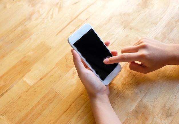 Femme utilisant un téléphone portable sur la table en bois se bouchent