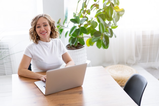 Femme, utilisation, ordinateur portable, séance bureau, bureau intérieur, à, plante d'intérieur