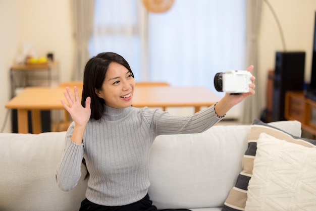 Une femme utilise un appareil photo numérique pour filmer à la maison.