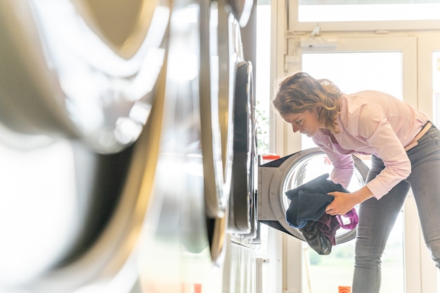 La femme utilise une buanderie publique. copie espace