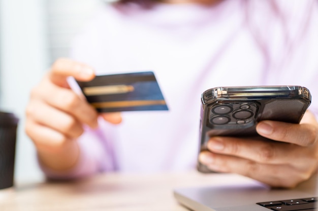 Une femme utilise une carte de crédit pour payer des achats en ligne sur une application mobile par smartphone