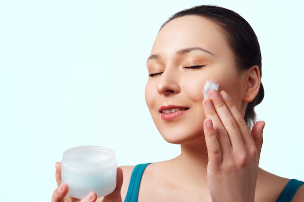 Une femme utilise une crème hydratante pour le visage