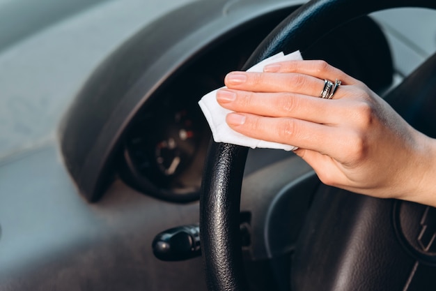 femme utilise un désinfectant au volant d'une voiture. Précautions pendant l'épidémie de coronavirus. Fusible de COVID-19. fille dans un masque médical dans une voiture.