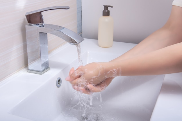 La femme utilise du savon et se lave les mains sous le robinet d'eau. Concept d'hygiène