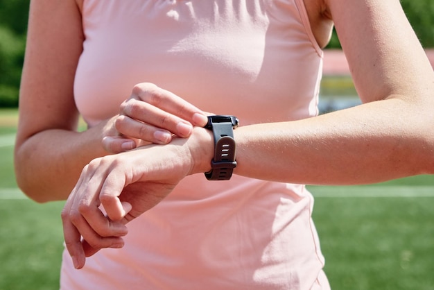 Une femme utilise une montre intelligente de remise en forme pour vérifier les résultats après l'entraînement sportif