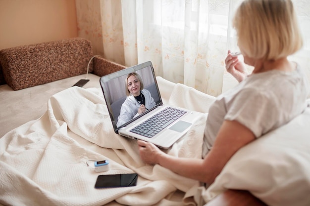 Une femme utilise un ordinateur portable sur le lit à la maison.