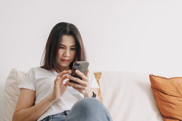 Une femme utilise un smartphone dans le salon de l'appartement