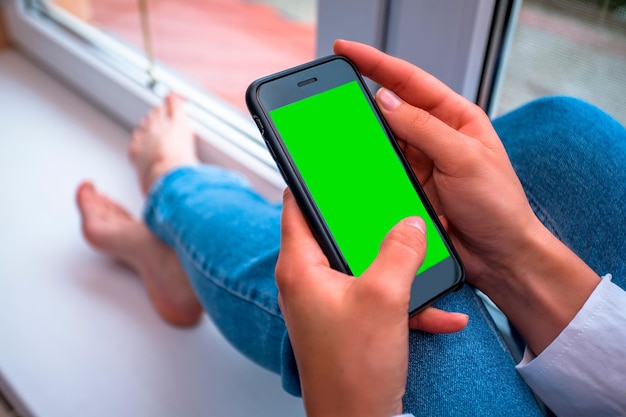 Une femme utilise un smartphone avec un écran vert.