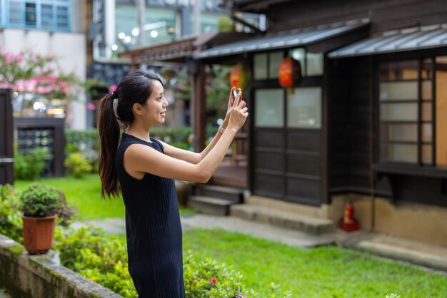 Une femme utilise un téléphone portable pour prendre une photo de la maison japonaise.