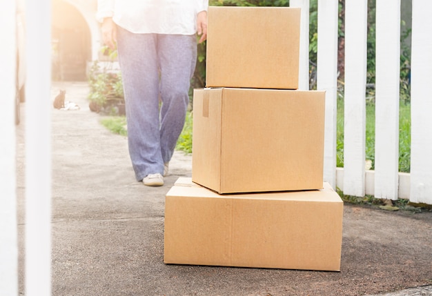 Une femme va à la boîte à colis livrée à la porte de la maison