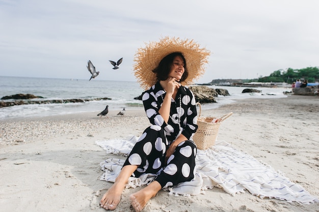 Femme en vacances d&#39;été portant chapeau de paille et robe de plage en appréciant la vue sur la mer