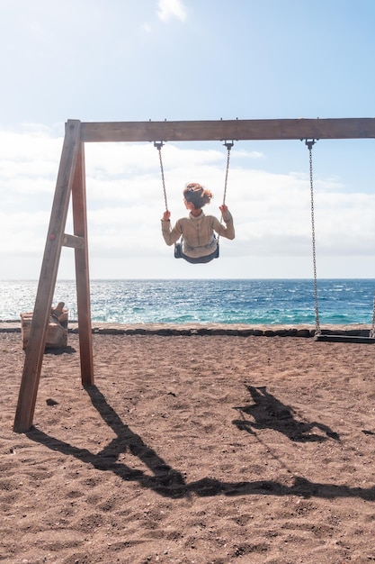 Une femme en vacances se balançant sur une balançoire sur la plage de l'île d'El Hierro Canaries