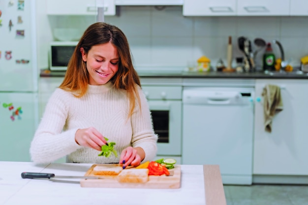 Femme végétarienne cuisinant un sandwich aux légumes dans la cuisine à la maison Placer la roquette