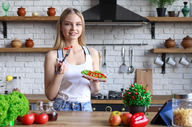 Une femme végétarienne mange de la salade dans sa cuisine, la cuisson des aliments végétaux