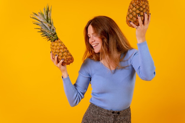 Femme végétarienne souriante avec une danse d'ananas coupée et une vie saine heureuse fond jaune