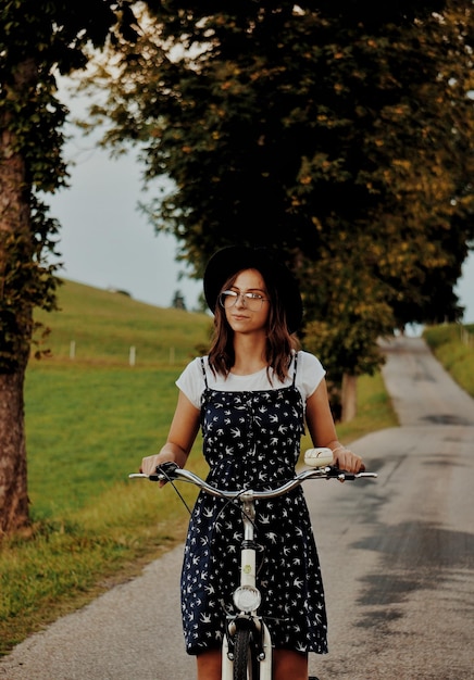 Photo femme avec un vélo debout sur le sentier contre les arbres