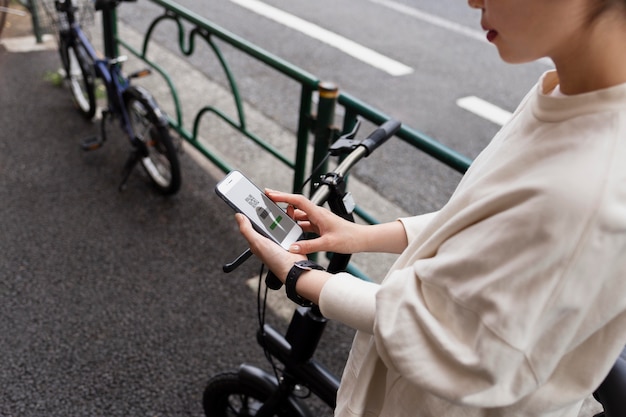 Photo femme avec vélo électrique dans la ville à l'aide de smartphone