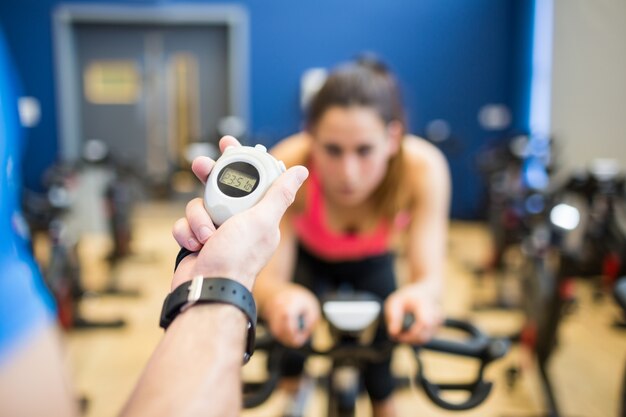 Femme sur un vélo d&#39;exercice avec entraîneur chronométrer