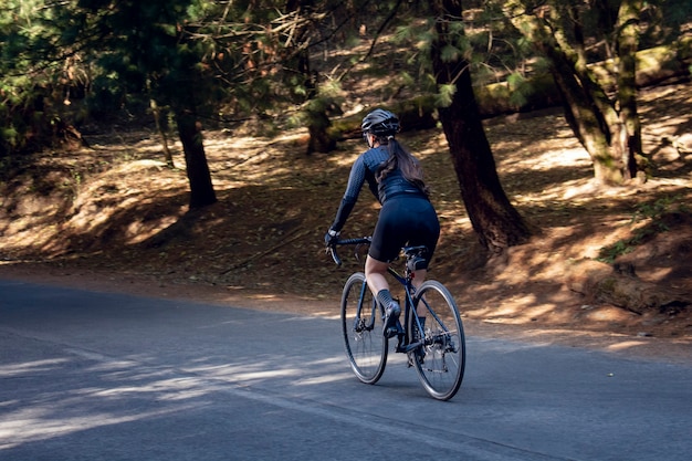 Photo femme en vélo de piste sur une route au milieu de la forêt concept de sport de plein air