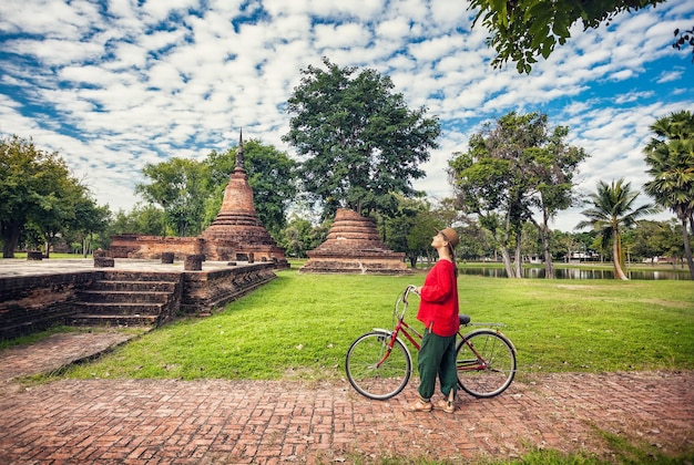 Femme à vélo près de ruines en Thaïlande