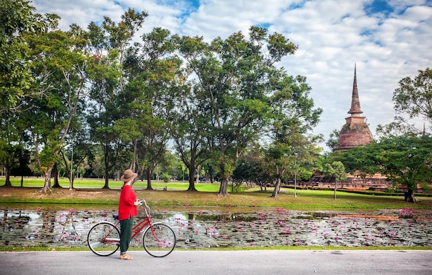 Femme à vélo près de temple en Thaïlande