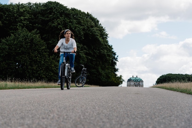 Femme à vélo sur une route de campagne contre des arbres