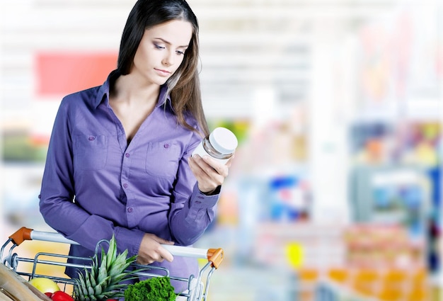 Femme vérifiant l'étiquetage des aliments en supermarché.