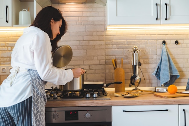 Femme vérifiant le pot avec de l'eau bouillante à la cuisine