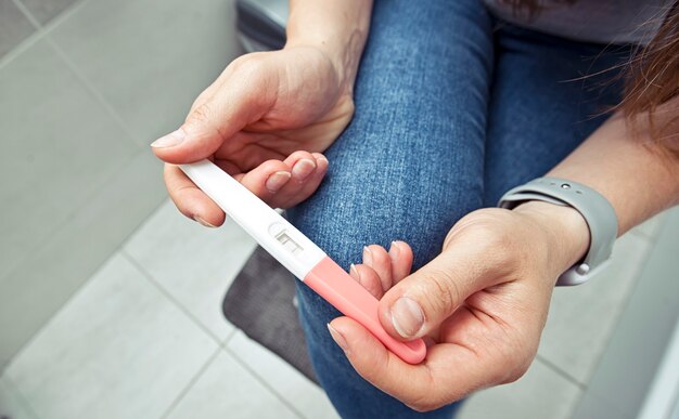 La femme vérifie le test de grossesse dans la salle de bain