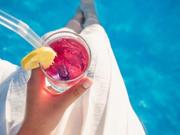 Femme avec verre à cocktail près de la piscine. Vue de dessus