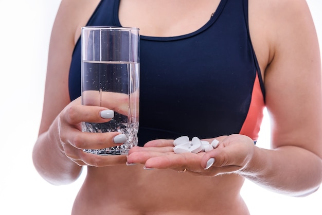 Femme avec verre d'eau et pilules en bouteille isolée