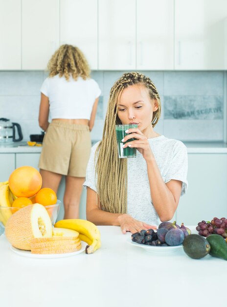 Femme avec un verre de smoothie détox naturel dans la cuisine des aliments biologiques et de la vitamine Tendance de l'alimentation végétarienne Concept végétalien Poids idéal et perte de poids Faire un menu de smoothie