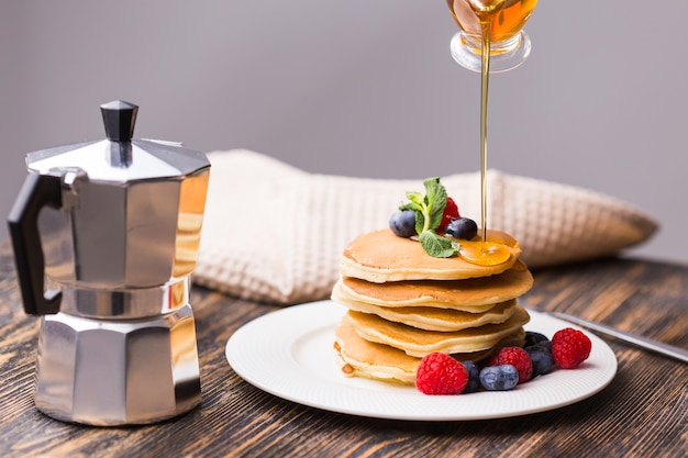 Femme versant du sirop d'érable sur de savoureuses crêpes