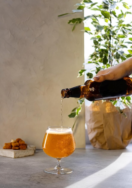 Une femme verse de la bière légère d'une bouteille sombre dans un verre sur un espace de copie de fond clair