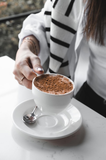 une femme verse du café dans une tasse de café