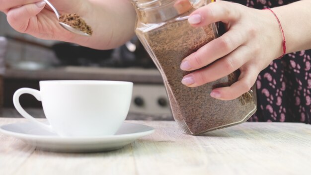 Une femme verse du café instantané dans une tasse. Mise au point sélective. Nature